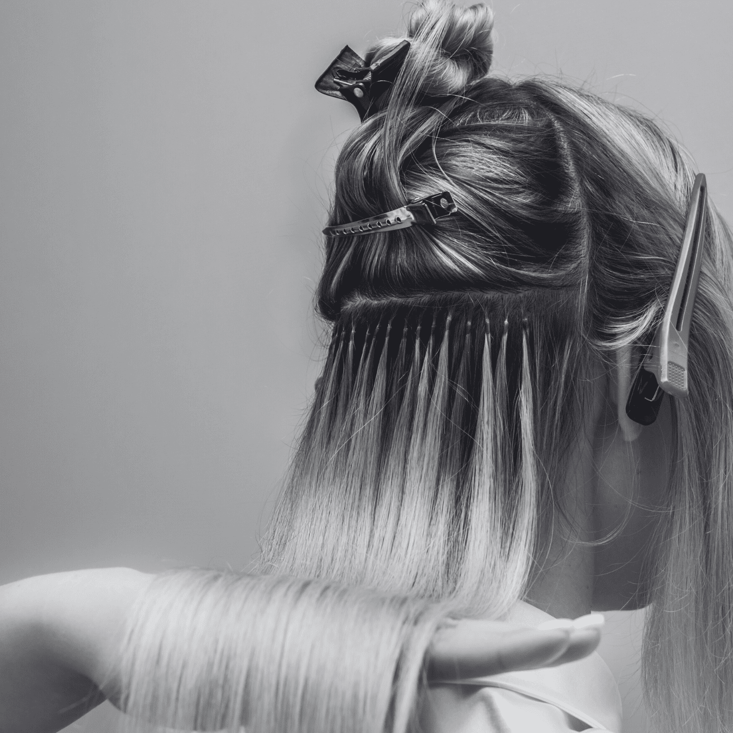 Hair extension application in progress with clips securing sections on a woman's head.