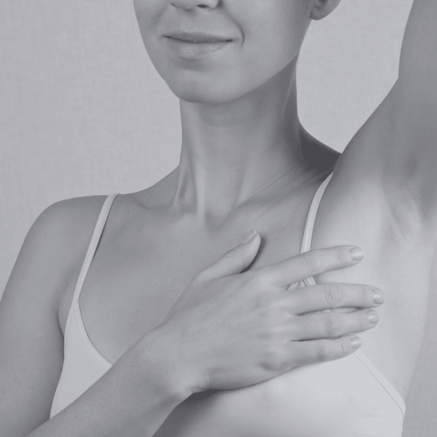 Woman checking underarm in a self-examination gesture against a plain background.